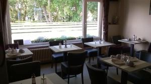 德哈恩Kokodor的餐厅设有桌椅和大窗户。