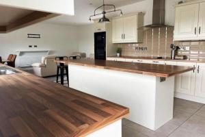 弗萨Aghadoe Millers - Modern 3 bed house Killarney的厨房配有白色橱柜和木制台面