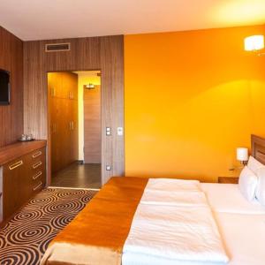 佩奇Sándor Hotel的一间卧室设有一张床和黄色的墙壁