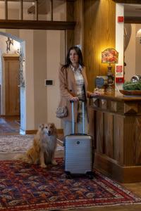 莫埃纳丽城多洛米蒂花卉酒店的一位带着手提箱站在狗旁边的妇女