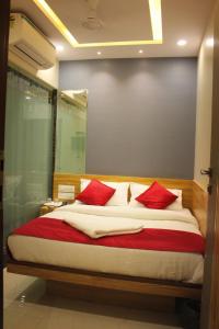 孟买MAROL METRO HOTEL MUMBAI的一间卧室配有一张带红色枕头的大床