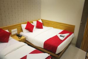 孟买MAROL METRO HOTEL MUMBAI的两张位于酒店客房的床,配有红色和白色枕头
