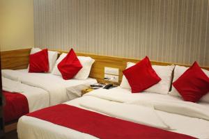 孟买MAROL METRO HOTEL MUMBAI的酒店客房 - 带两张带红色枕头的床