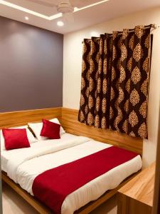 孟买MAROL METRO HOTEL MUMBAI的一间卧室配有一张带红色枕头的大床