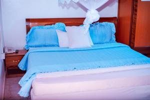 基加利SILVER HOTEL APARTMENT Near Kigali Convention Center 10 minutes的蓝色的床,配有蓝色和白色的枕头