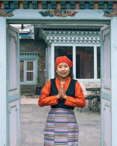 NamcheMountain Lodges of Nepal - Namche的站在门前的女人,手在前面