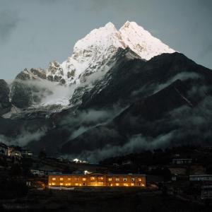 NamcheMountain Lodges of Nepal - Namche的山前有一座建筑,上面有雪覆盖