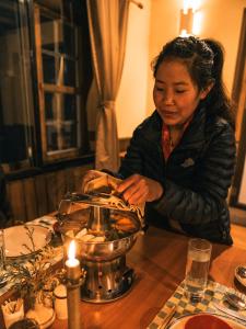 NamcheMountain Lodges of Nepal - Namche的坐在桌子上的带蜡烛的女人