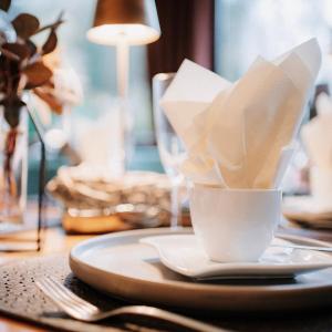 布罗登巴赫佩菲尔餐厅酒店的一张带餐盘的桌子和一杯餐巾纸