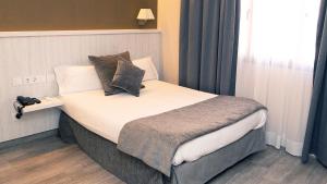 巴塞罗那Hotel Coronado的一间卧室配有一张大床和枕头