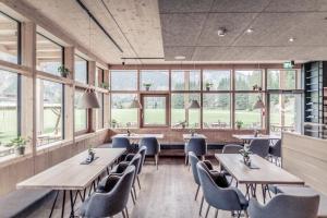 ElmenBoutique Hotel LechZeit的餐厅设有木桌、椅子和窗户。