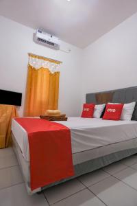 沙马林达Super OYO 92626 Good Sleep 4 Inn Dcos Syariah的一间卧室配有一张带红色枕头的床