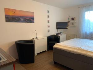 奥斯赛拜-屈隆斯博恩Yachthafenresidenz-Wohnung-8106-9412的一间卧室配有一张床、一张书桌和一台电视。