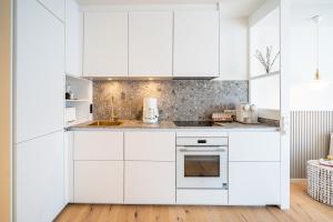 诺伊霍夫Quartier am Strand - App 05的白色的厨房配有白色橱柜和电器