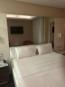 PerafitaMotel Flamingo的一间卧室配有两张带白色床单和枕头的床。