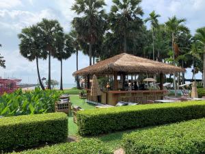 邦萨雷Condo Centerviews Bangsaray Beach的一间种有棕榈树的稻草小屋的餐厅