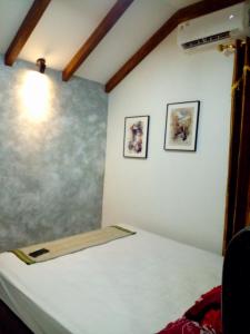巴图卡拉巴图卡拉斯法亚民宿的墙上有两张照片的房间的一张床位