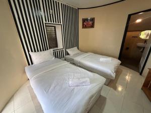 帕干岛Soukaina Beach Bungalow的配有白色床单的酒店客房内的两张床