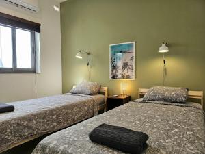 MġarrMalta Unique Penthouse Spacious Terrace-Sleeps 8的酒店客房设有两张床和窗户。