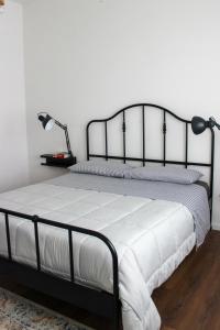 CeggiaCasa Delisa的一间卧室配有一张黑色框架床和白色床单。