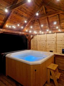 TokarniaW Sosnach的木制客房内的大型热水浴池,配有灯