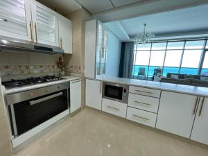 阿吉曼Luxurious Sea View - Beach Front的厨房配有白色橱柜和炉灶烤箱。