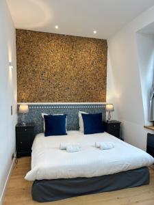 迪纳尔Le Royal XIX Dinard vue mer luxe的卧室配有带蓝色枕头的大型白色床