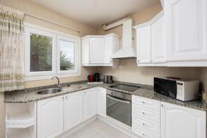 蒂亚斯Villa Reyes的厨房配有白色橱柜、水槽和微波炉