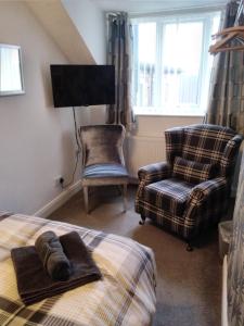 布里德灵顿Bagshaw Bed & Breakfast的一间卧室配有一张床、一把椅子和电视。
