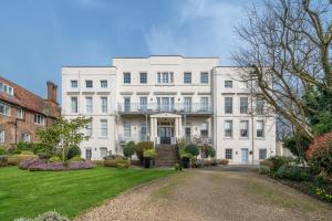 东莫尔西Riverside 1 Bed Flat near Hampton Court Palace的一座大型白色建筑,在庭院里设有阳台