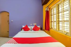 库斯哈尔纳加尔OYO Flagship 68124 Shangri-la Hotel的一间卧室配有红色和白色枕头的床