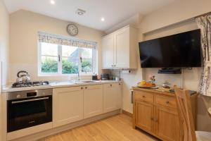 Thornham MagnaThe Lily Pad Suffolk的厨房配有白色橱柜和平面电视。