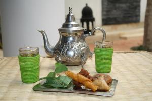 梅克内斯里亚德亚姆查旅馆的餐桌,带一盘食物和茶壶