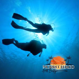 努基Morro Terco Hotel Boutique的两个人在海洋里游泳,太阳在他们身后