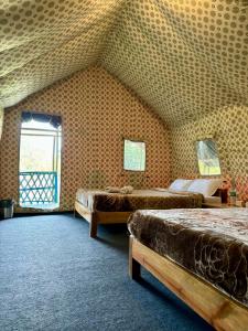 卡齐兰加Kodom Bari Retreat, Kaziranga的一间设有两张床的卧室,位于带屋顶的房间