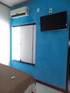 阿拉卡茹HOTEL AL MARE ATLANTICO的卧室设有蓝色墙壁,墙上配有电视