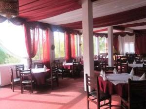 米德勒特Hôtel El Ayachi的一间配备有桌椅和红色窗帘的用餐室