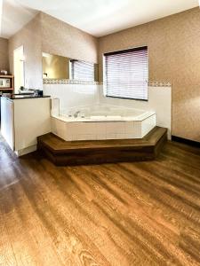 坎卢普斯Prestige Aberdeen Lodge Kamloops的带浴缸的大浴室和木地板