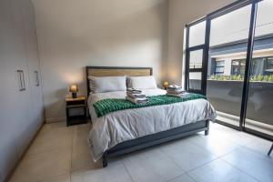 比勒陀利亚Luxurious Upmarket Apartment的一间卧室设有一张床和一个大窗户