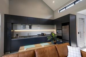 比勒陀利亚Luxurious Upmarket Apartment的厨房配有黑色橱柜和木桌