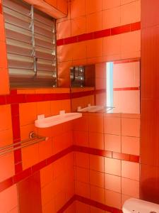 瓦加杜古Villa JFK2的橙色瓷砖浴室设有水槽和镜子
