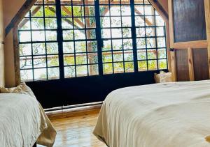危地马拉安地瓜Earth Lodge的一间卧室设有两张床和大窗户