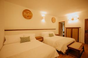 莱瓦镇Hotel La Corada的一间卧室设有两张床,墙上挂着一个时钟。