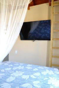 卡拉伊瓦Chalés Cabocla da Lua的一间卧室配有一张带窗帘的床和一台电视