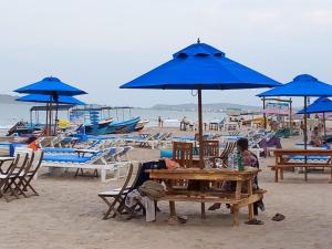 亭可马里So-J海滩别墅的坐在海滩上带蓝伞的桌子上的人