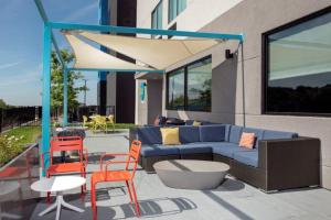 圣安东尼奥Tru By Hilton San Antonio North的庭院设有蓝色的沙发和橙色的椅子。