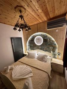 吉诺卡斯特"Mani Guest House"的一间卧室设有一张带石墙的大床