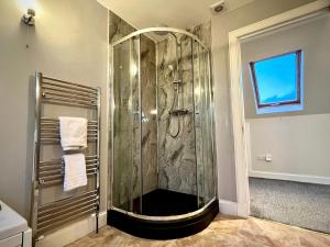 波特里Blacksmith holiday cottage near Portree in central Skye的浴室里设有玻璃门淋浴