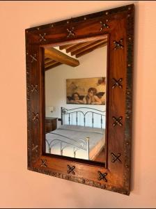 拉达-因基安蒂LOCANDA PODERE LE VIGNE的墙上的镜子,里面装有床