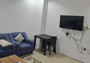 Qarārنور المنازل للوحدات السكنية的客厅配有蓝色椅子和带电视的桌子